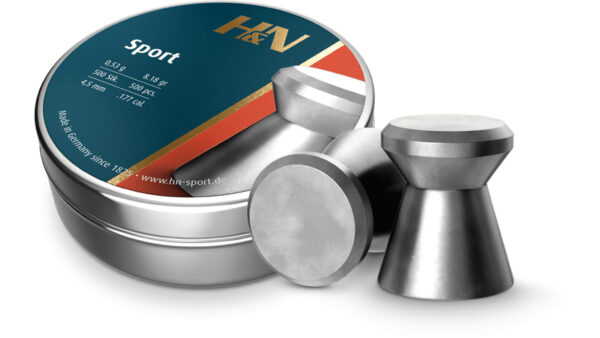 Round metal tin labeled H&N Sport with a blue-orange design, placed beside several silver dumbbell weights, suggesting a sport or fitness product