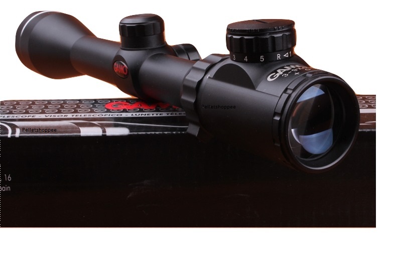 Black riflescope with adjustment knobs resting on a boxed product.